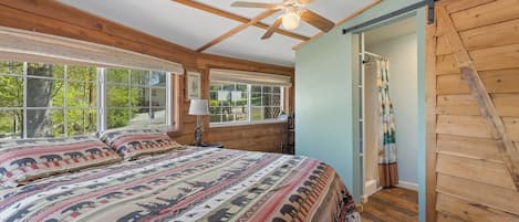 Un dormitorio con una cama grande, ventilador de techo y vistas al exterior.
