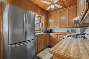 Una cocina con armarios de madera, un refrigerador de acero inoxidable, un microondas y una encimera de madera.