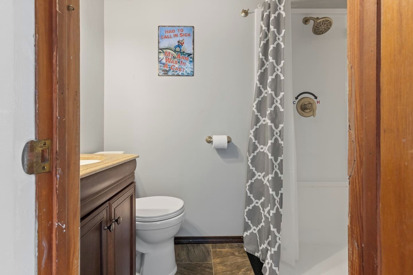 Ein Badezimmer mit Toilette, Duschvorhang und einem an der Wand befestigten Toilettenpapierhalter.