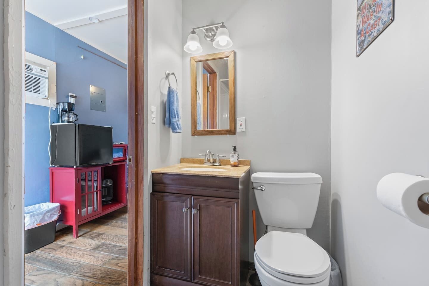 A compact bathroom with a toilet, sink, and mirror.