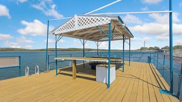A wooden deck with a covered seating area, a table, and a bench.