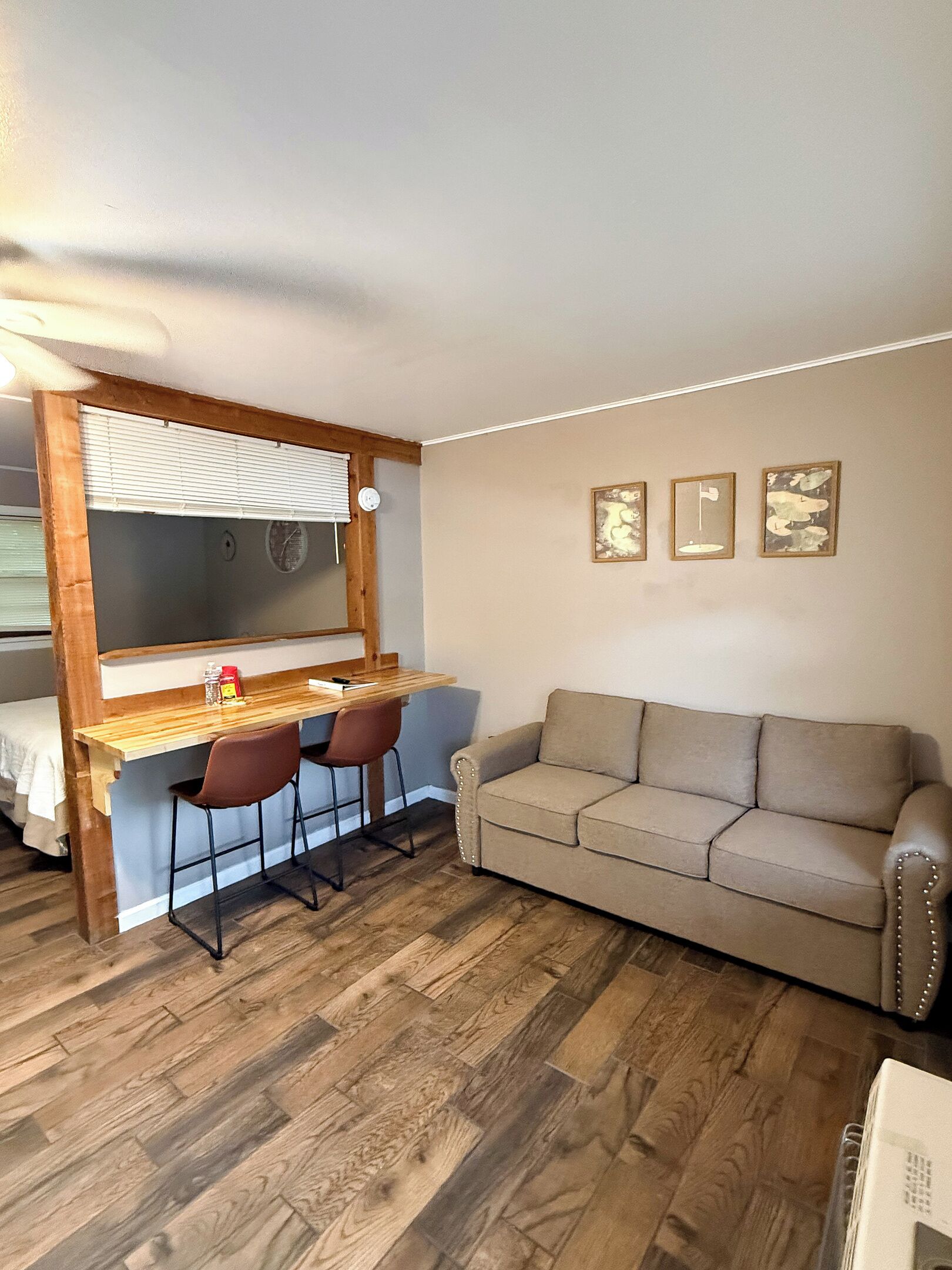 A compact living space with a wooden desk, two chairs, a sofa, and a bed.
