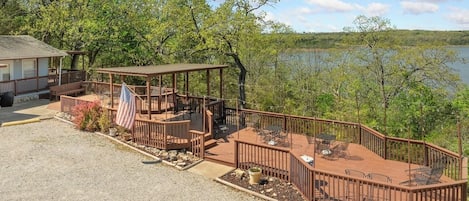 A deck with outdoor seating and a small pavilion, overlooking a body of water.