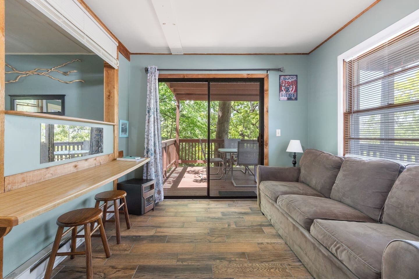 A room with a wooden bar, a sofa, a dining table, and a view of the outdoors.
