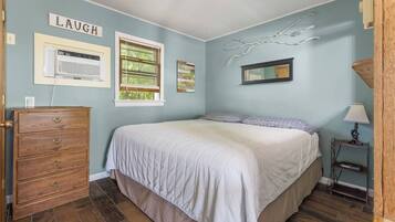 A bedroom with a bed, dresser, and wall decorations including a sign that says 'LAUGH'.