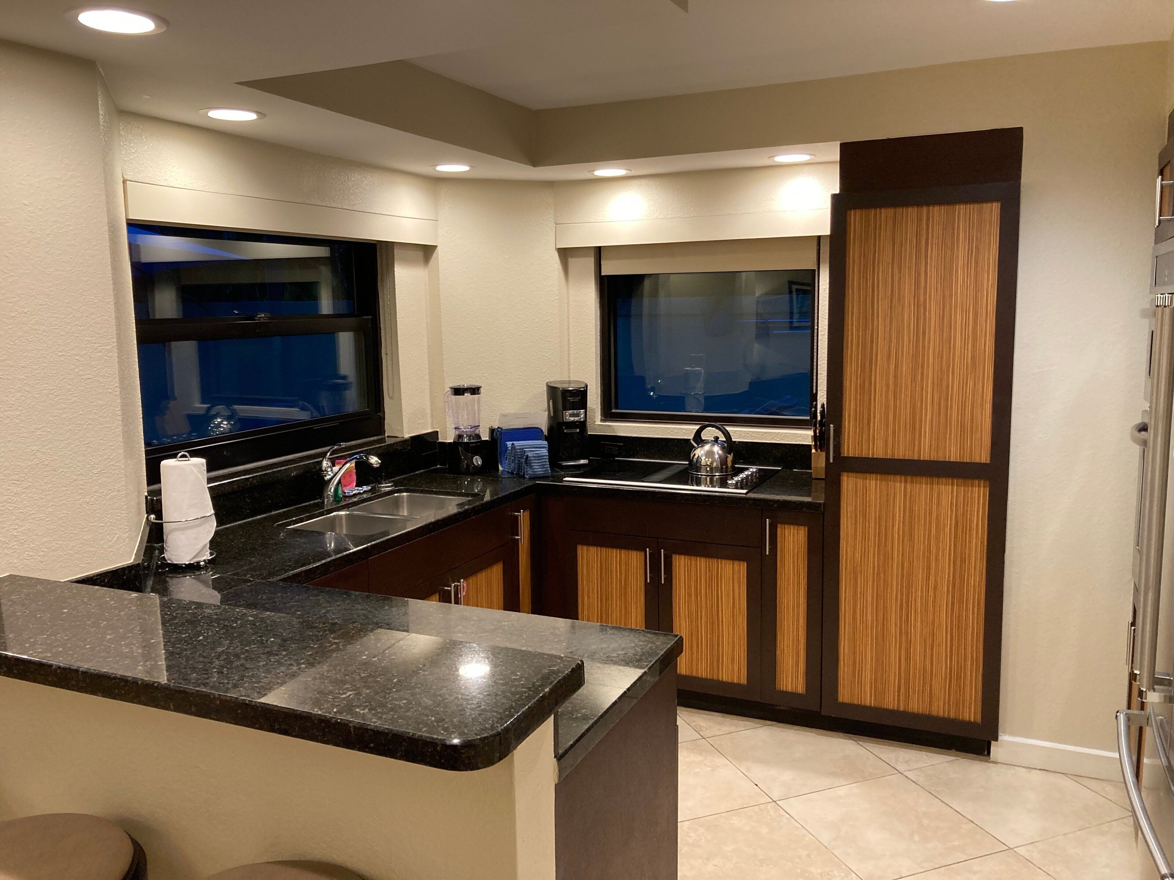 A modern kitchen with a central island, built-in appliances, and a large window.
