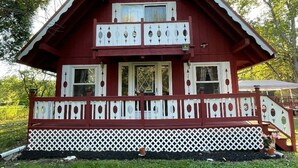 A two-story red wooden house with a white balcony and lattice fence.