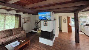 A living room with a sofa, a coffee table, a fireplace, and a television mounted on the ceiling.
