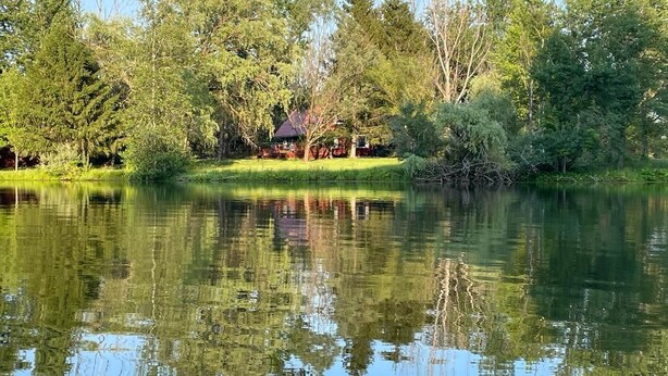 A house by a lake with reflections of trees and a clear sky.