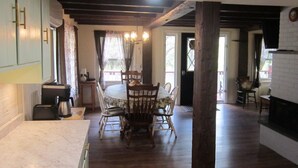 A spacious kitchen with wooden flooring, a dining table with chairs, and a fireplace.