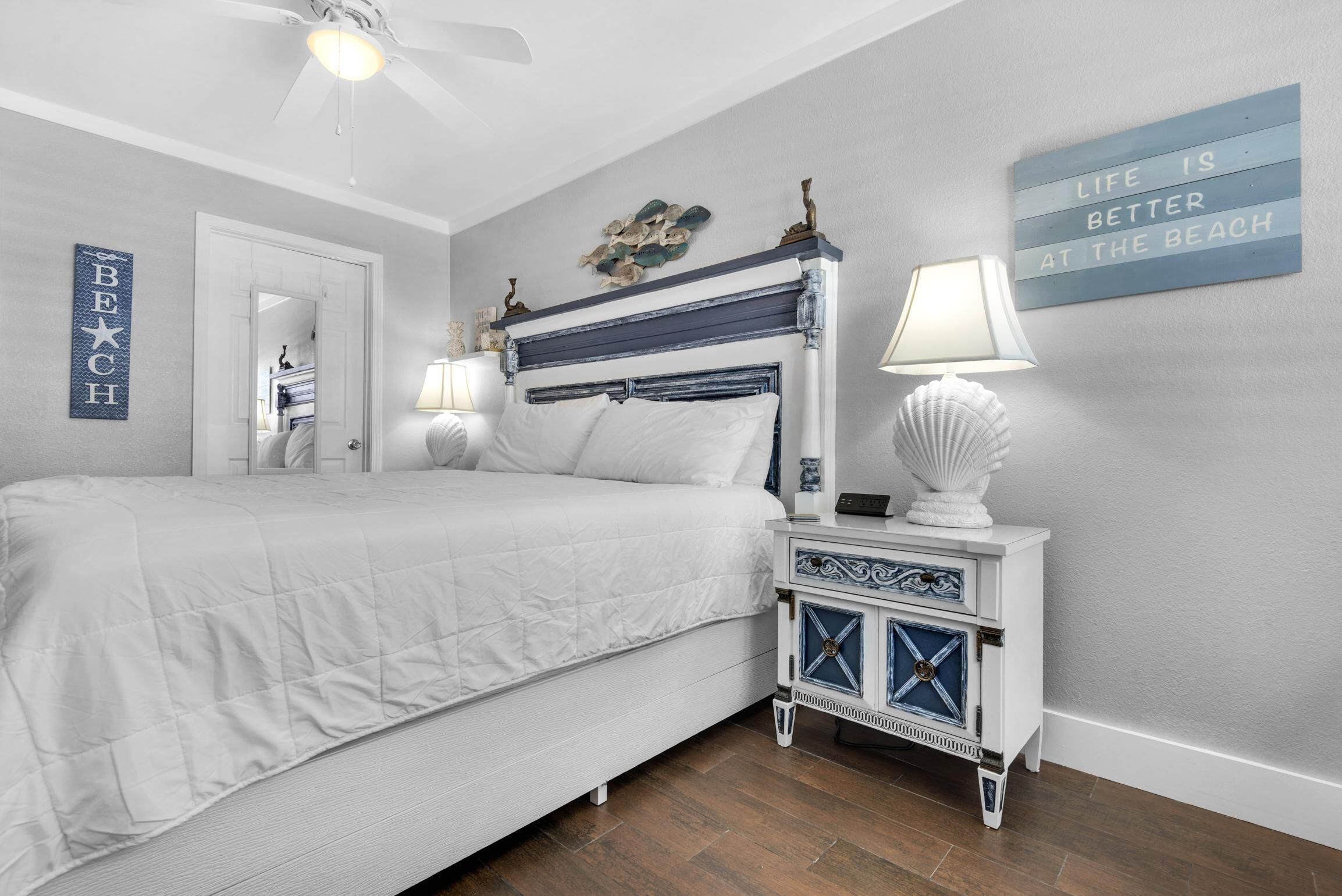 A bedroom with a bed, bedside lamps, a decorative wall piece, and a door.
