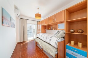 Une chambre à coucher avec un lit, des armoires en bois, une étagère ornée d’objets décoratifs et un tableau accroché au mur.