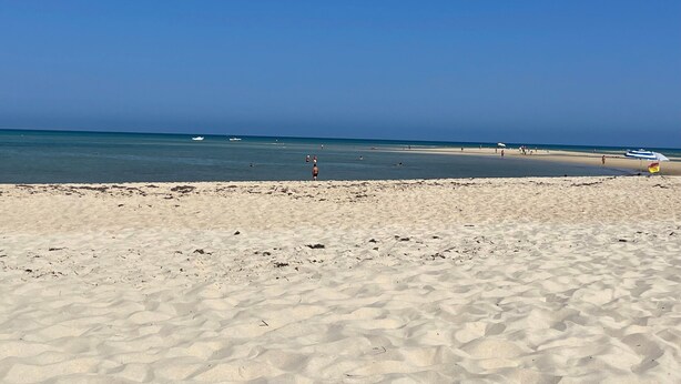 A beach with clear skies, calm water, and a few boats. - Holiday Home 'Linda' with Private Terrace, Wi-Fi and Air Conditioning (Olhão)