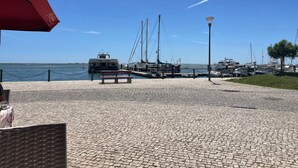 A marina with boats docked, a paved walkway, and a bench. - Holiday Home 'Linda' with Private Terrace, Wi-Fi and Air Conditioning (Olhão)