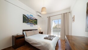 A bedroom with a bed, nightstands, a lamp, a painting, and a view of the outside. - Holiday Home 'Linda' with Private Terrace, Wi-Fi and Air Conditioning (Olhão)