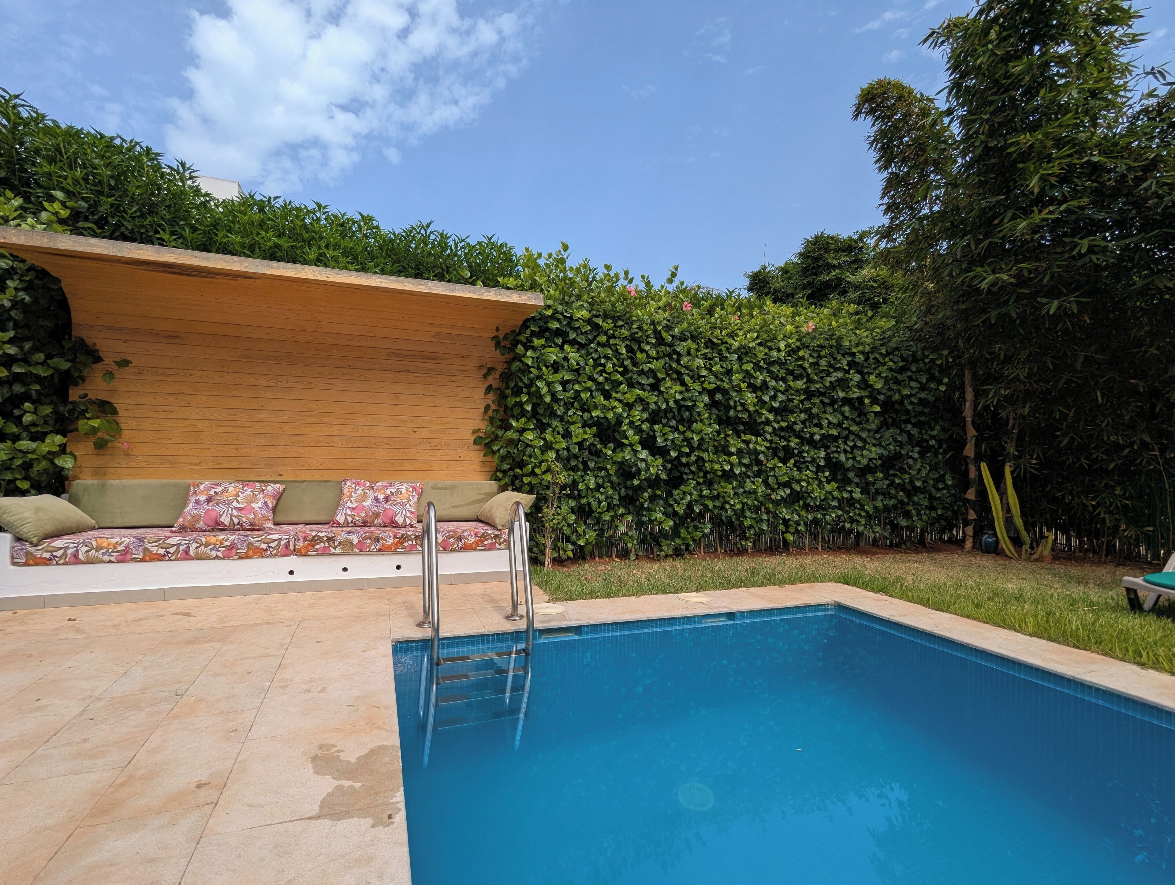 Une piscine dotée d’une terrasse en bois et d’un espace détente avec des coussins.