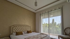 Un dormitorio con una cama grande, una mesita de noche, una silla y vistas a zonas verdes.
