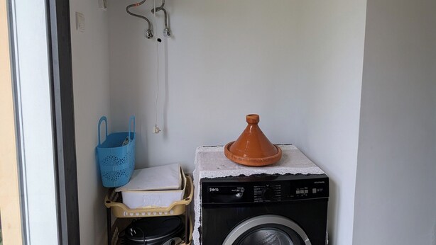 A compact laundry area with a washing machine, a water heater, and a blue laundry basket. - Lovely 3-bedroom villa with Private  Pool in Tamaris (Tamaris)