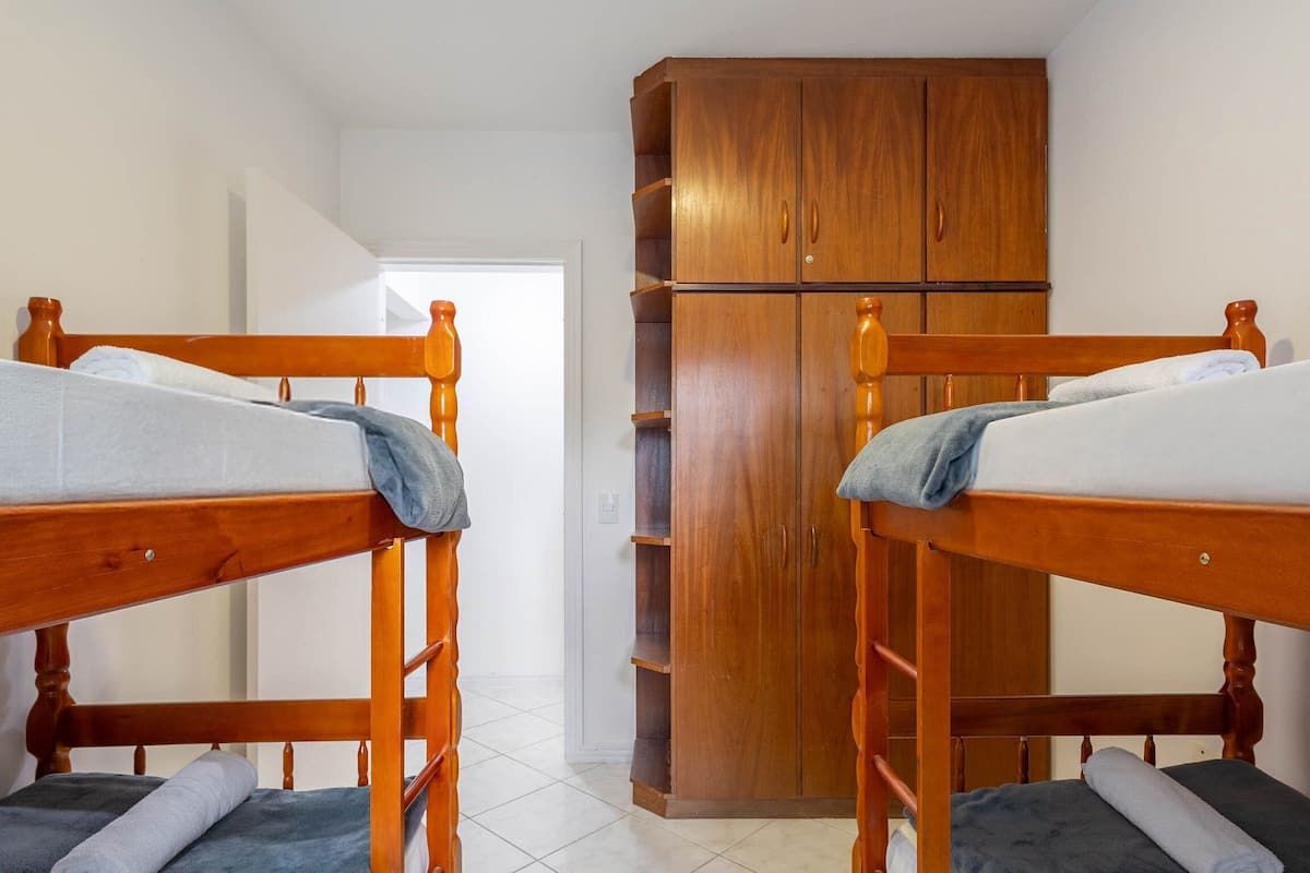 A room with two bunk beds, a wooden wardrobe, and a white door.