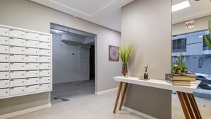 A reception area with a white reception desk, a plant, and a wall-mounted sign. - Apt w/ Balcony & BBQ 290m From the sea Cau0199 (Itapema)