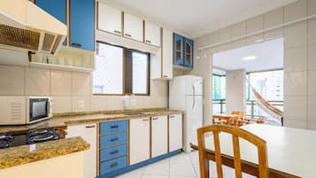 A modern kitchen with a microwave, stove, and refrigerator. There is a dining area with a table and chairs.