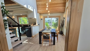 Ein modernes Interieur mit Holzboden, einem Essbereich mit Tisch und Stühlen sowie einer Treppe, die in eine obere Ebene führt.