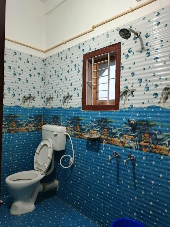 A bathroom with a blue tiled wall featuring marine life and a window. - Rudra homes (Guwahati)