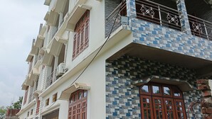 A multi-story residential building with balconies, a tiled facade, and a parked motorcycle. - Rudra homes (Guwahati)