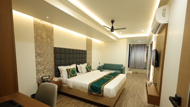 A modern hotel room with a large bed, a desk, and a television. - Hotel Heaven Blue (Rajkot)