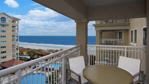 Een balkon met uitzicht op de oceaan, witte relingen en een zwembad.