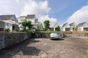 A residential area with houses, a paved driveway, and a covered car. - Villa Dangka Kintamani Mitra RedDoorz (Bali)