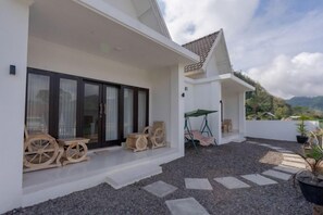 A covered outdoor seating area with a table and chairs, a swing, and a view of the landscape.