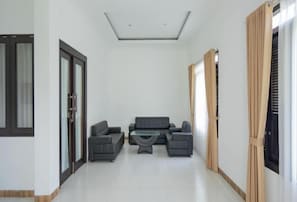 A modern living room with a sofa set, a glass coffee table, and a ceiling light fixture.
