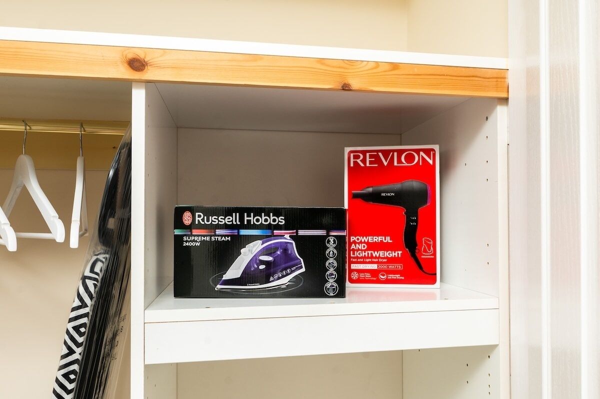 Hyllyllä on Russell Hobbs -merkkinen silityrauta ja Revlon-merkkinen hiustenkuivaaja niiden alkuperäisissä pakkauksissa.