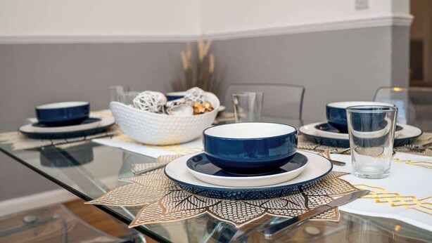 A dining table set with blue and white dishes, a bowl of snacks, and a glass of water. - Modern 3 bed perfect for contractors and families (Maltby)