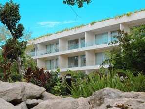 Un hotel de varios pisos con balcones, rodeado de exuberante vegetación y rocas.