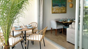 Ein Essbereich mit einem runden Tisch, Korbstühlen und einem großen Gemälde an der Wand.
