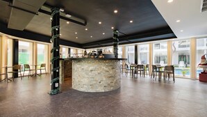 Ein großzügiger Innenbereich mit einer zentralen Steinbar, Sitzgelegenheiten und großen Fenstern für natürliches Licht.