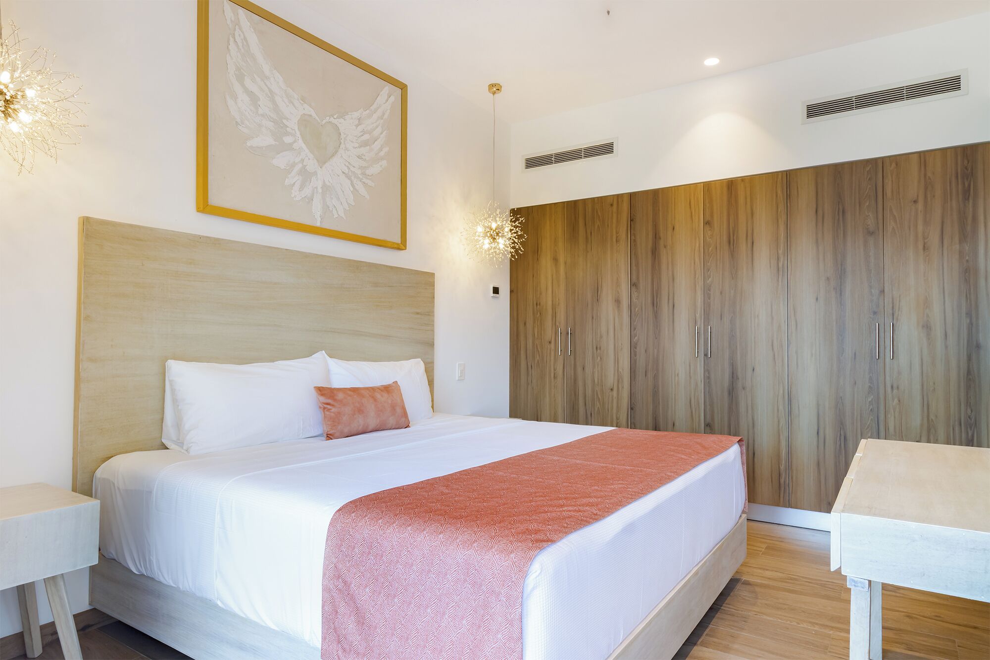 A hotel room with a large bed, a wooden wardrobe, and a bedside table.