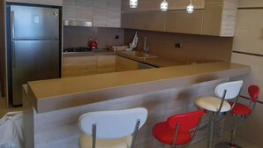 A modern kitchen with a central island, stainless steel appliances, and red bar stools.