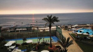 A pool area with a view of the ocean at sunset.
