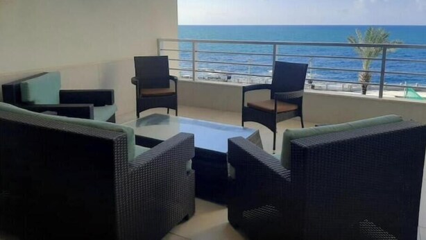 A balcony with wicker furniture and a view of the sea.