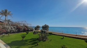 A coastal view with a grassy area, trees, and a clear blue sky. - Silvia's romantic Byblos beach Studio (Byblos)