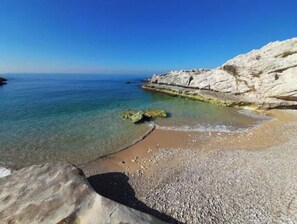 A coastal beach with clear water, pebbly shore, and white rock formations. - Beach apartment with Pool and direct beach access (Tabarja)