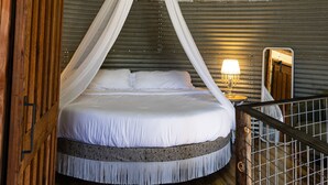 A tent-style room with a bed under a canopy, a chandelier, and a wooden floor. - Seven Star Silo - stay in luxury while you take in the tranquility of the Ranch! (Valley View)