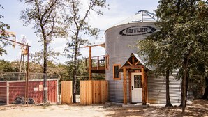 A rustic barn with a silo labeled "BUTLER" and a wooden structure attached to it. - Seven Star Silo - stay in luxury while you take in the tranquility of the Ranch! (Valley View)