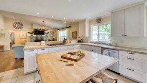 A spacious kitchen with a large island, white cabinetry, and a view to the outside.