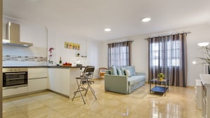 A modern kitchen with a built-in oven, a dining area with a light blue sofa, and a living room with a grey sofa. - Holiday Apartment 'Rolycar 101' with Private Terrace and Wi-Fi (Icod de los Vinos)