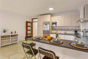 A modern kitchen with a central island, a refrigerator, microwave, and a sink.