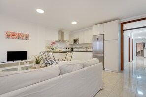 A modern kitchen with white cabinetry, a stainless steel refrigerator, and a microwave.